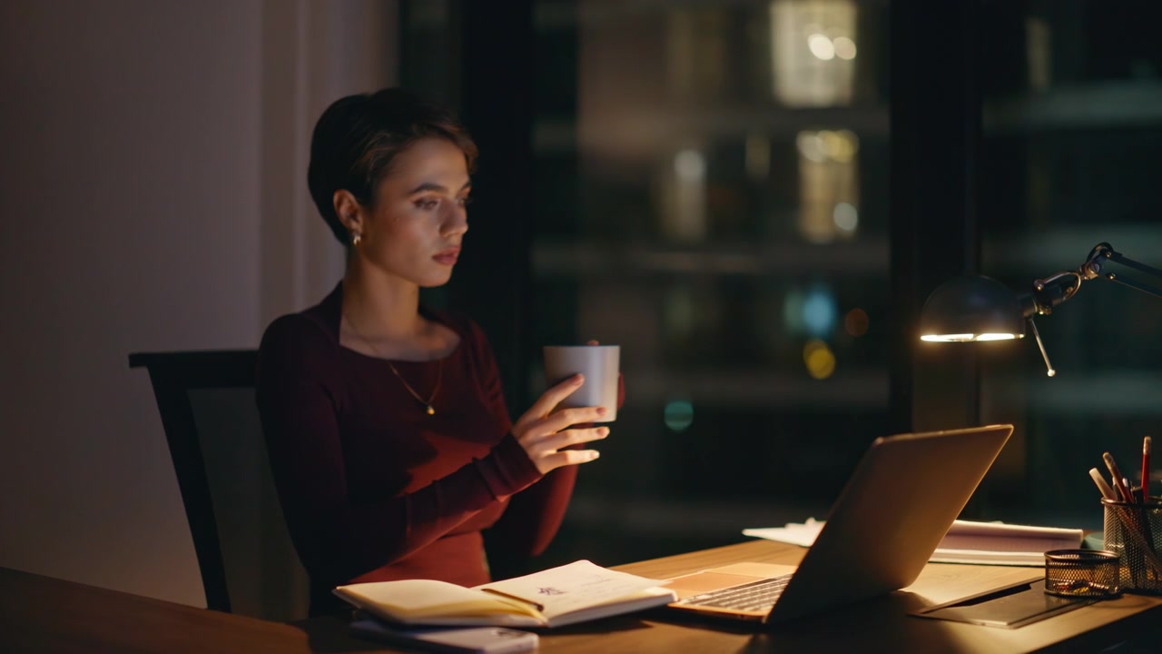 Pensive entrepreneur looking screen late night office. Woman holding coffee cup