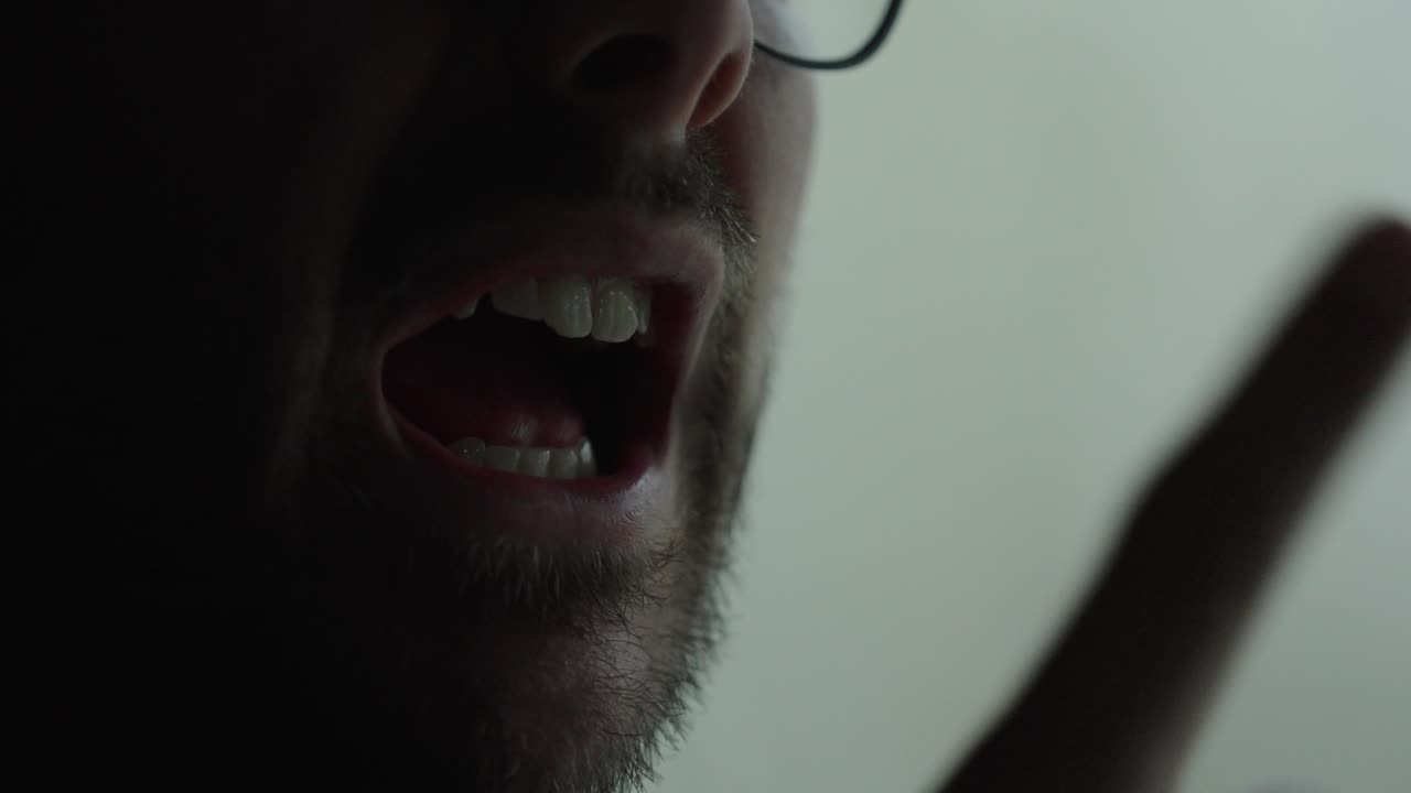 Intense close-up of a man yelling with visible anger and tension in a low-light cinematic setting. Ideal for concepts like aggression, conflict, stress, emotional breakdown, and dramatic storytelling
