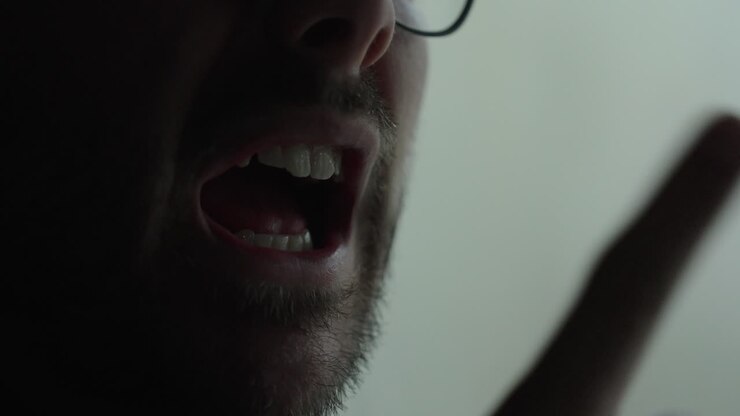 Intense close-up of a man yelling with visible anger and tension in a low-light cinematic setting. Ideal for concepts like aggression, conflict, stress, emotional breakdown, and dramatic storytelling