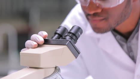 student looking through microscope while one is watching