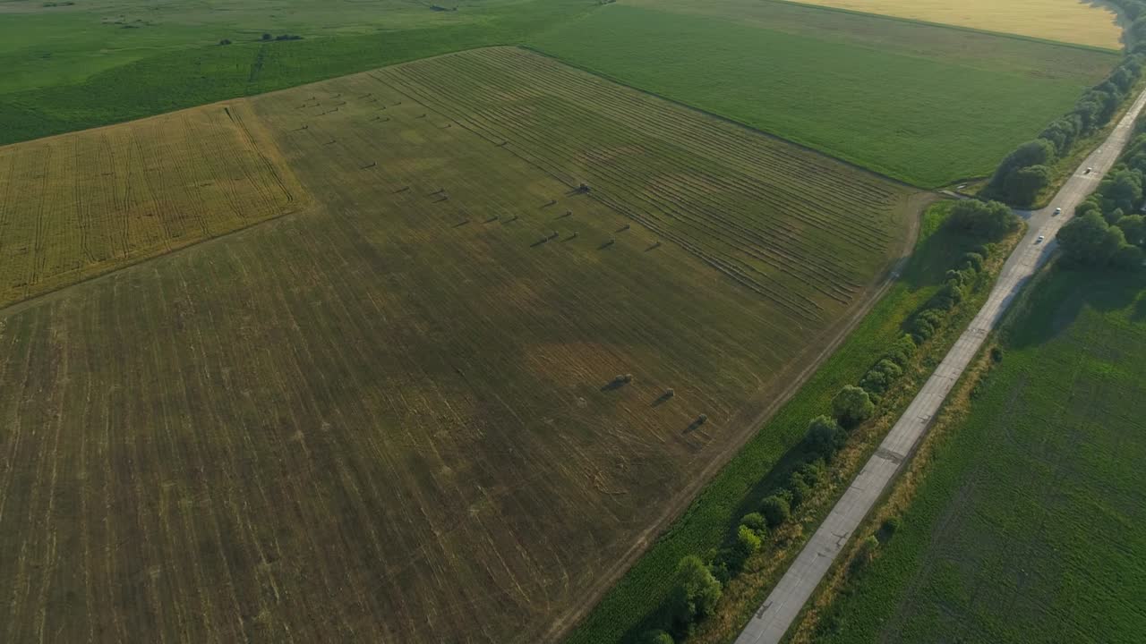 Aerial view tractor baling machine making silage bales on farmland, cut wheat