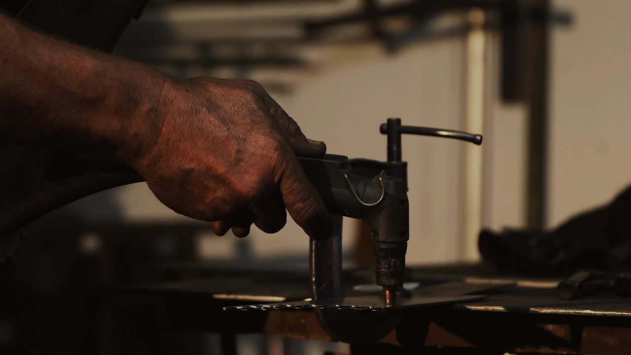Operator aligning torch to metal plate in fabrication igniting arc as data graphs showing metrics