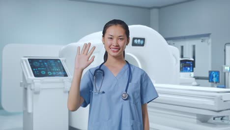 asian female doctor waving hand and smiling to camera with mri machine