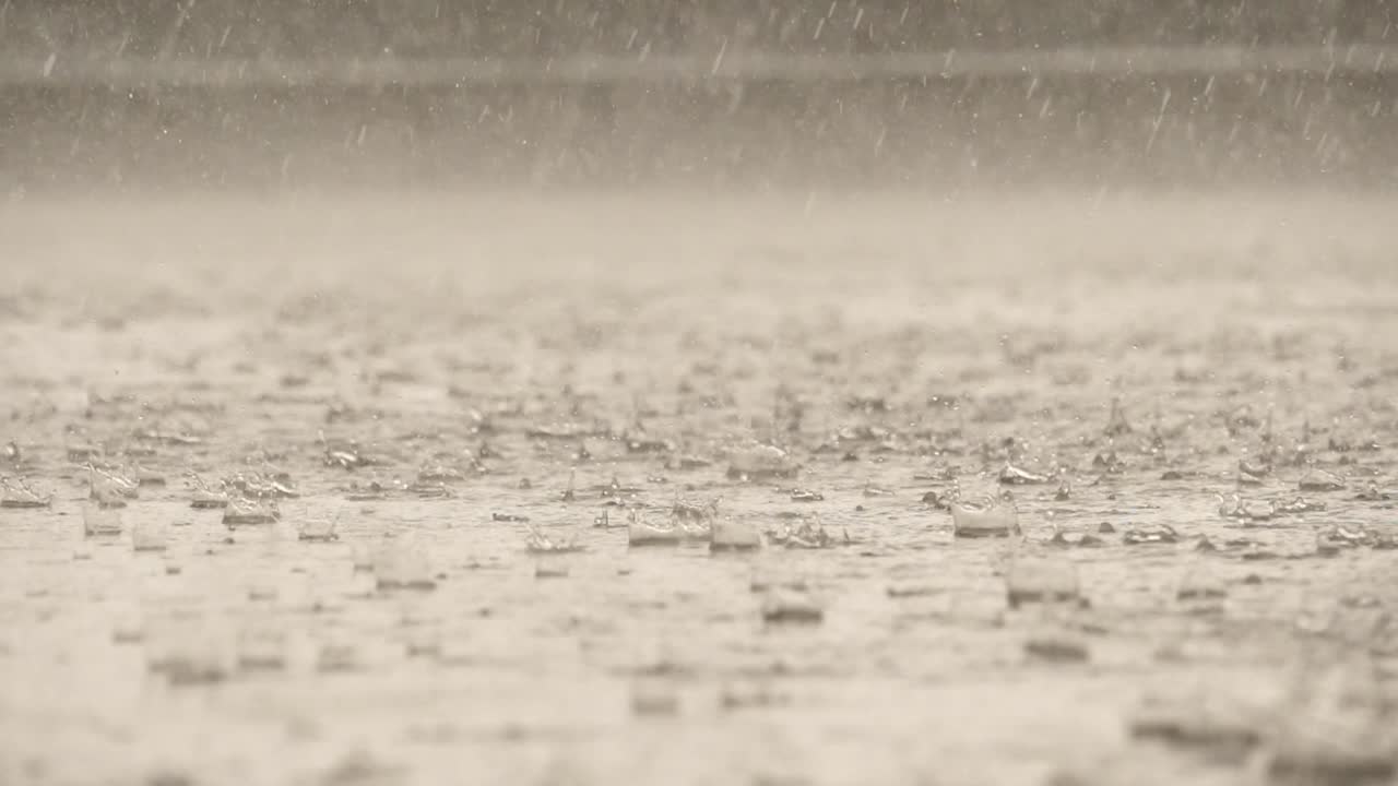 Slow motion speed close up scene of dropping pattern when raining falling against water surface on cement floor
