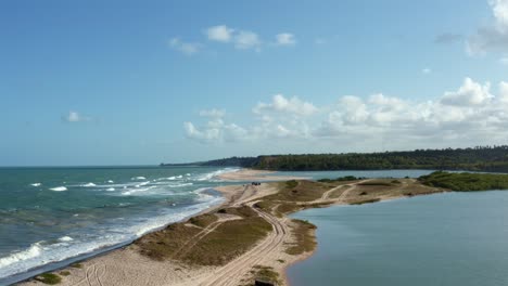 Descending-aerial-drone-shot-of-the-beautiful-coastline-of-Gramame-where-the-ocean-meets-the-river-near-the-tropical-beach-capital-city-of-Joao-Pessoa-in-Paraiba,-Brazil-on-a-warm-summer-day