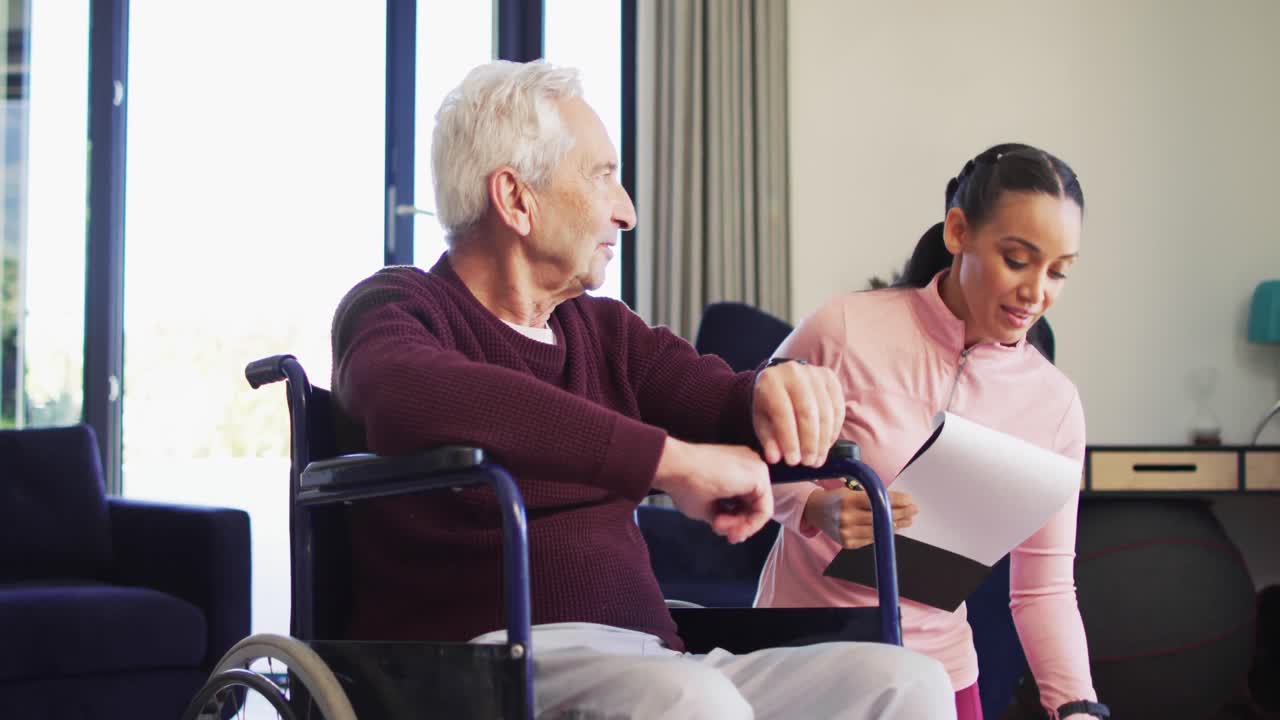 Video of happy biracial female physiotherapist exercising with caucasian senior man