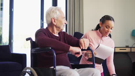 Video of happy biracial female physiotherapist exercising with caucasian senior man