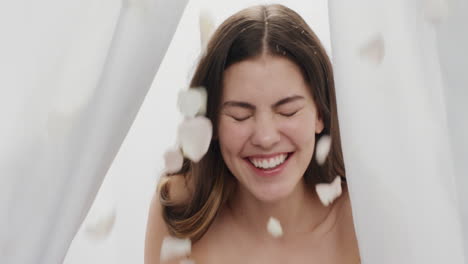 Retrato-Hermosa-Mujer-Joven-Pétalos-De-Rosa-Cayendo-Sobre-Una-Atractiva-Mujer-Sonriendo-Disfrutando-Del-Lujo-Entre-Sábanas-En-Concepto-De-Belleza-De-Fondo-Blanco