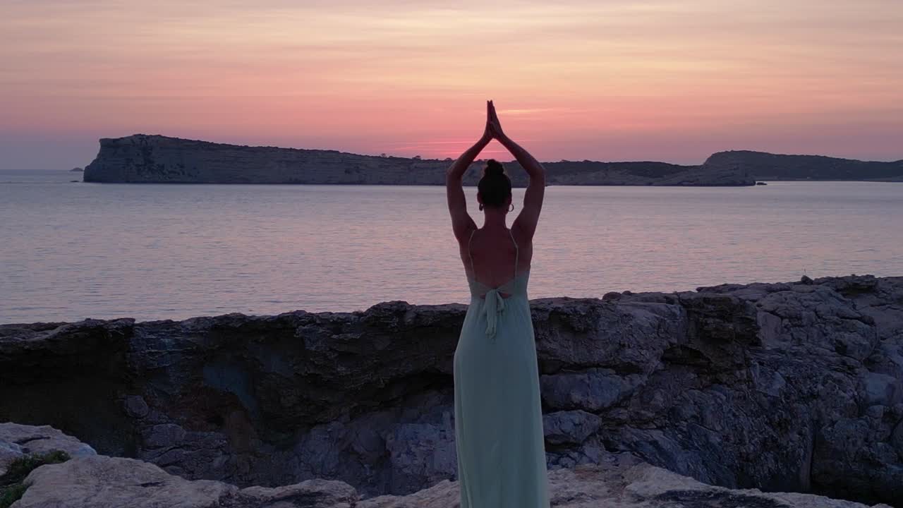 Yoga Hippie Girl at sunset with island in the background, Ibiza, Spain. Stunning aerial view flight speed ramp hyper motion time lapse