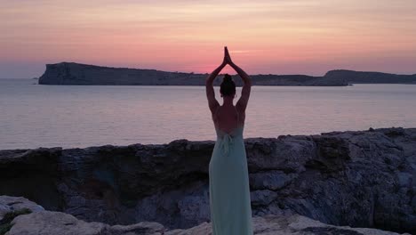yoga hippie girl at sunset with island in the background, ibiza, spain. stunning aerial view flight speed ramp hyper motion time lapse