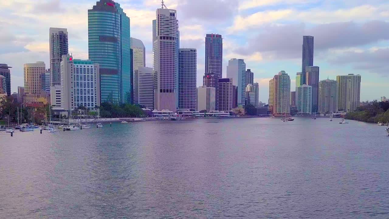 Vista aérea em movimento para frente e inclinando para cima da margem do rio do CBD da cidade de Brisbane