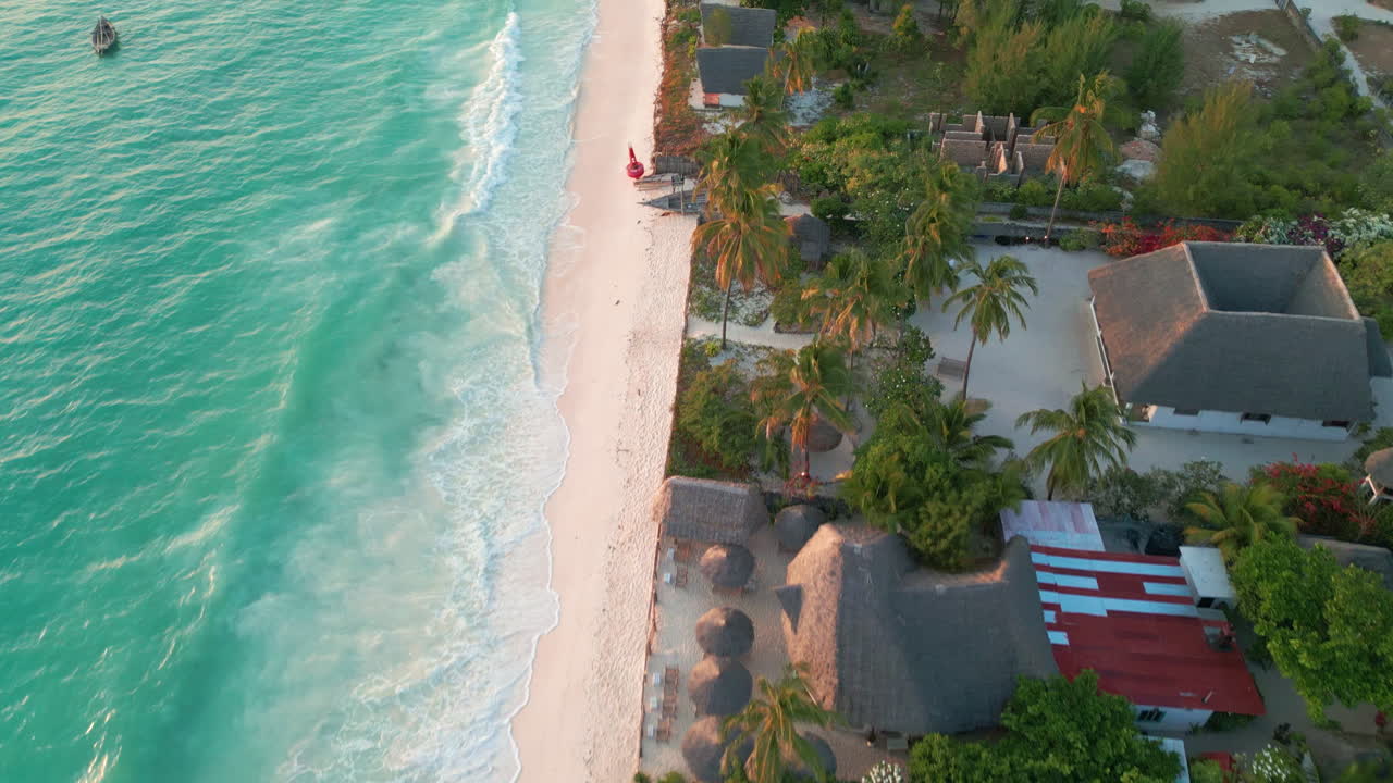 vista aérea de una tranquila playa vacía con villas con techos de escotilla