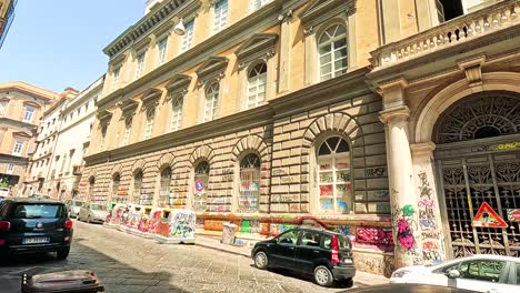 cars pass by a graffiti-covered building in naples