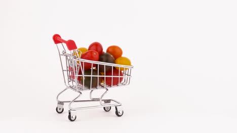 un carrito de supermercado en movimiento lleno de tomates de uva multicolores. aislados en el fondo blanco. primer plano. macro.