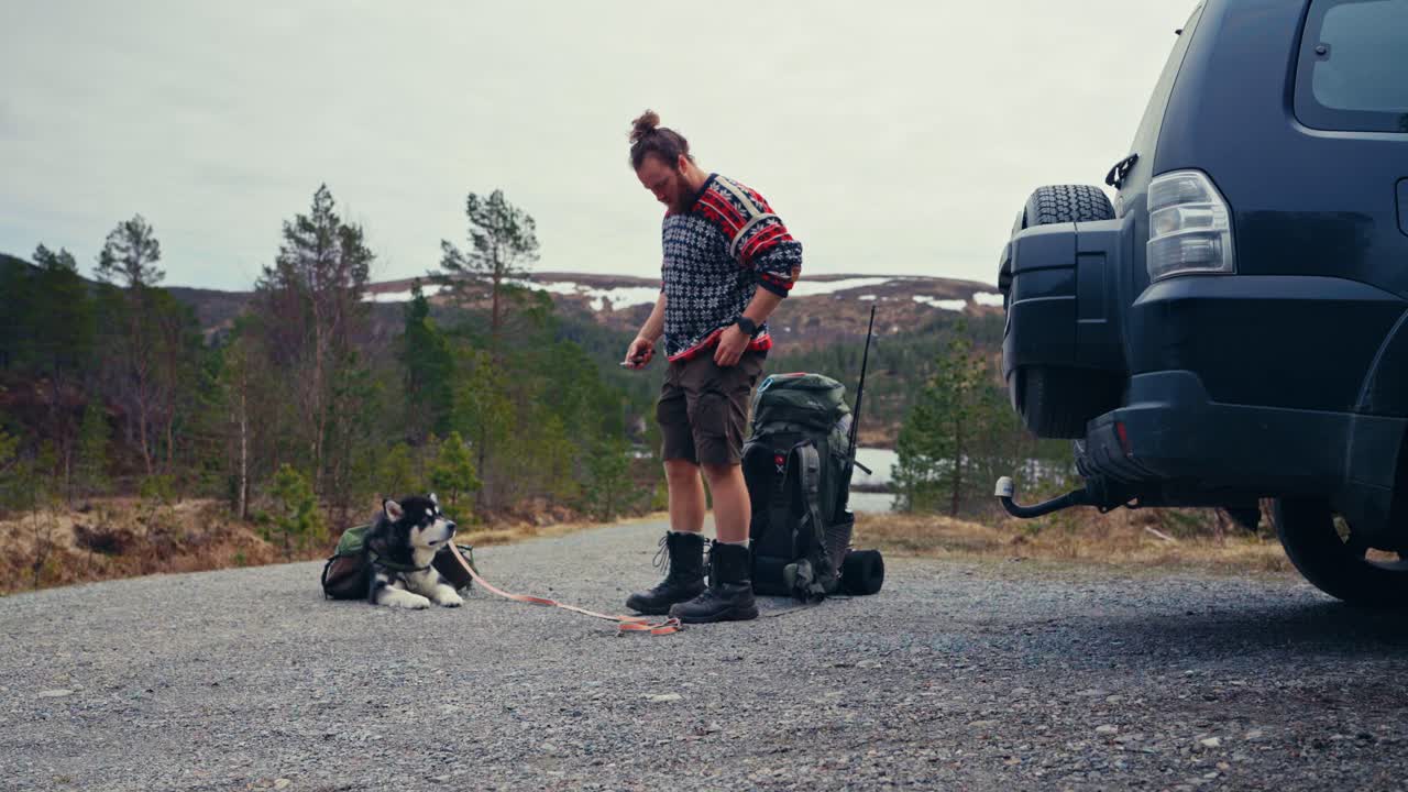 A Hiker, Accompanied by His Dog, Hoists a Heavy Backpack Near the Shores of Reinsjøen in Åfjord, Trøndelag, Norway - Static Shot