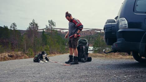 a hiker, accompanied by his dog, hoists a heavy backpack near the shores of reinsjøen in åfjord, trøndelag, norway - static shot