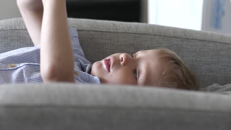 young boy laying on couch and talking, indoors static view