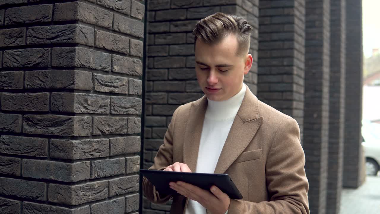 Elegant smiling man with tablet looking at camera