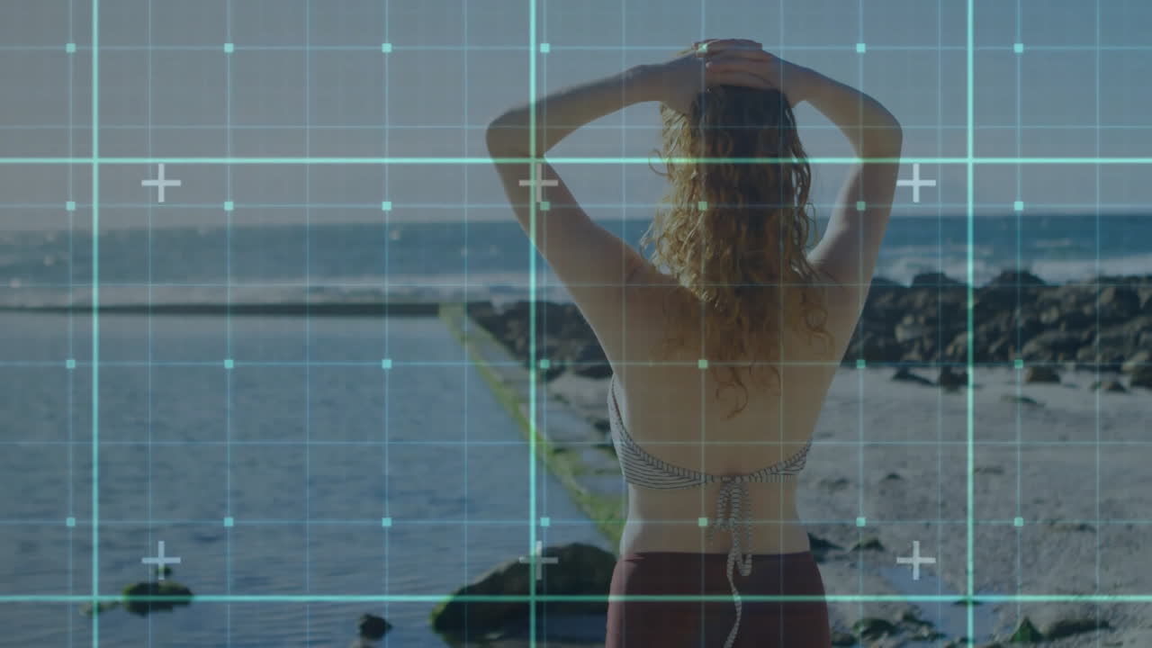 Standing by ocean, woman with digital grid overlay, animation concept