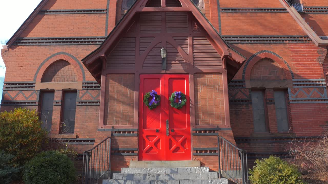 미국 코네티컷주 노거턱에 있는 세인트 마이클 성공회 정문 문은 크리스마스 화환으로 장식되어 있습니다.