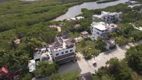 wide angle drone shot panning downwards of hotels and resorts surrounded by a jungle and mangroves on the tropical island of holbox in mexico shot in 4k