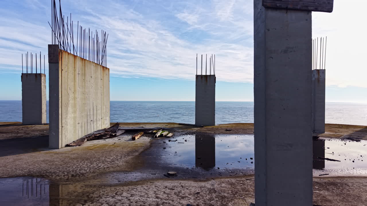 Concrete wall stands alone by the sea under a clear sky at sunset, reflecting the beauty and solitude of nature's boundaries
