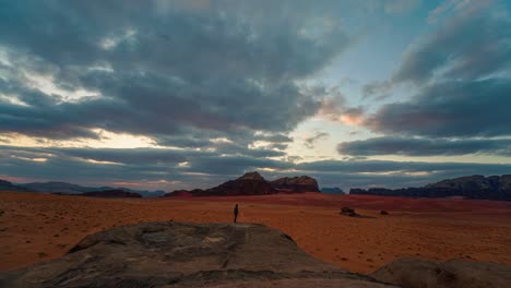 Sunset-cloud-time-lapse-of-one-young-man-at-famous-Wadi-Rum-Bedouin-desert,-historic-UNESCO-heritage-landscape,-Jordan