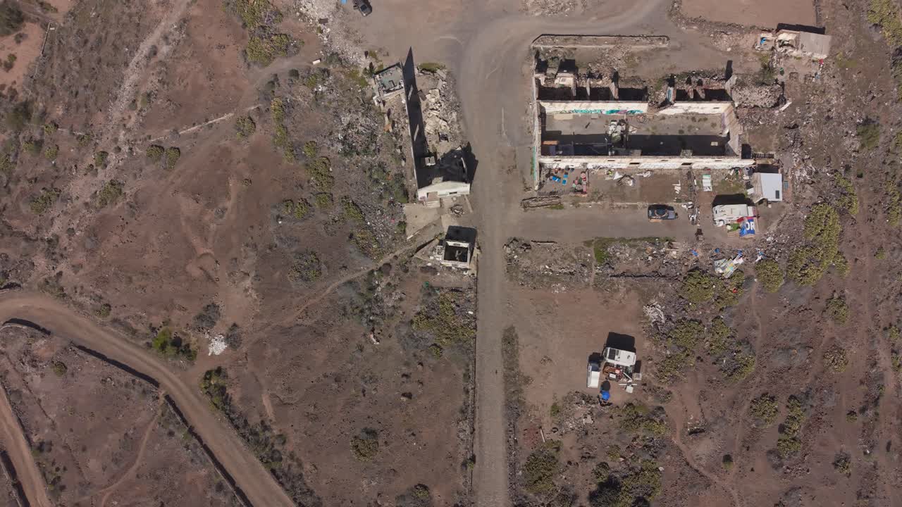 Sentiero tra rovine con baracche nelle Isole Canarie, che evoca la storia.