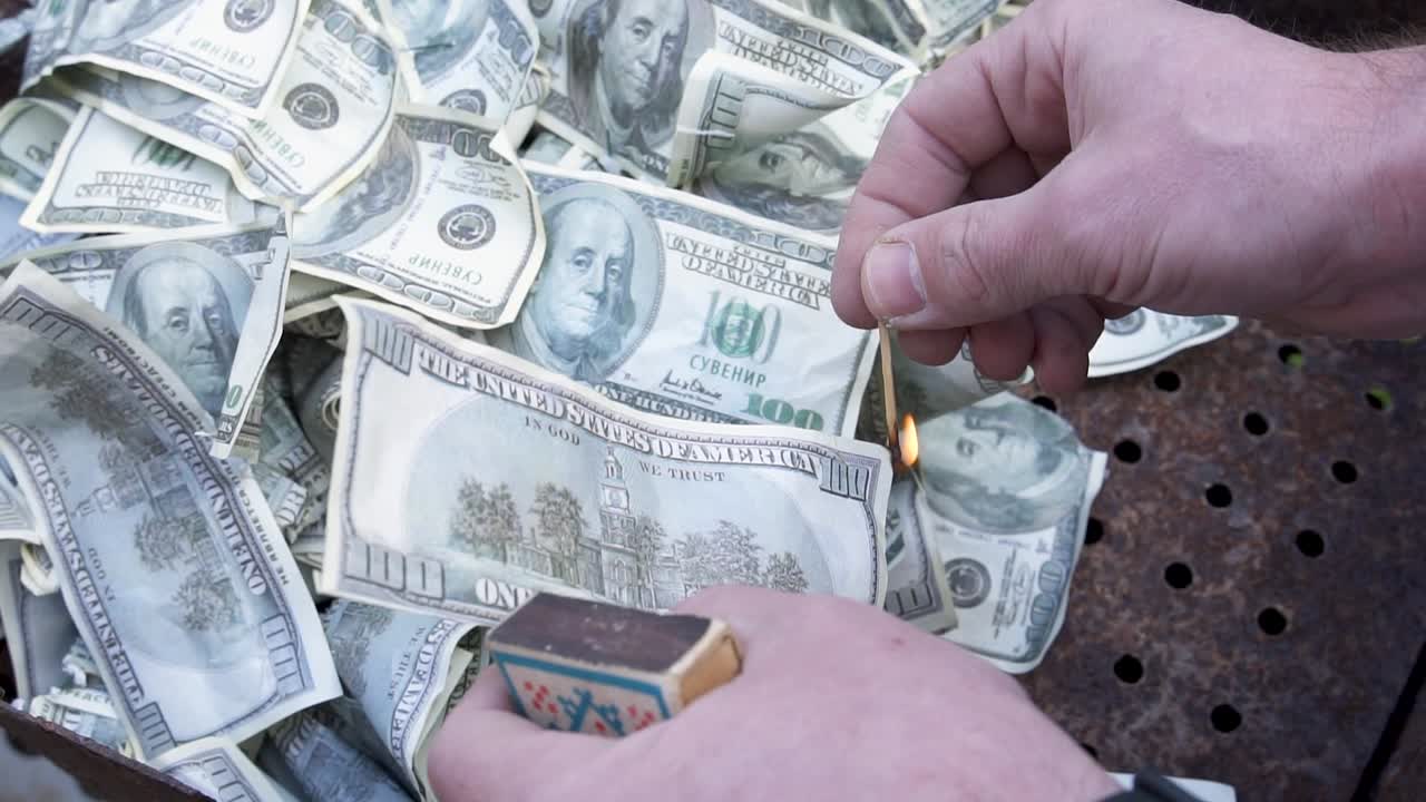 Lighting a match by strike on box. Burning counterfeit dollars. Souvenir in the trash