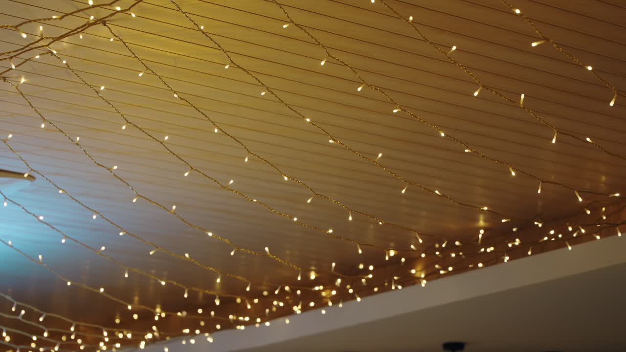 String lights hanging from a ceiling, creating a warm, festive ambiance in an indoor setting