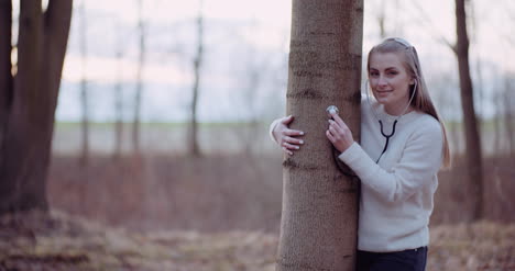 woman uses a stethoscope and examines a tree in the forest 5