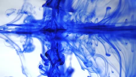 Blue-smoke-ink-on-a-white-background,-spills-of-colored-paint-on-a-transparent-liquid,-drop-of-blue-ink-falling-in-water,-drops-of-watercolor-paint,-shooting-studio