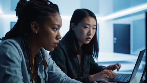 focused collaboration: two women engaged in intense digital work in a modern, tech-driven environment highlighting concentration and teamwork