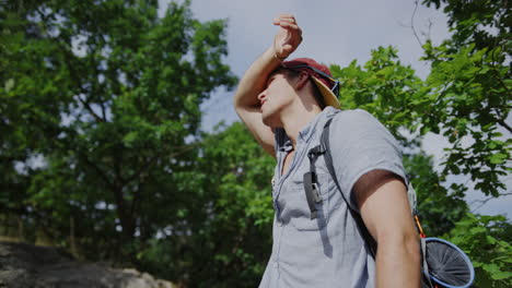 man looking into the sun, sunny athletic young guy, snapback hat, summer vibes, hiking in the forest, trail walking