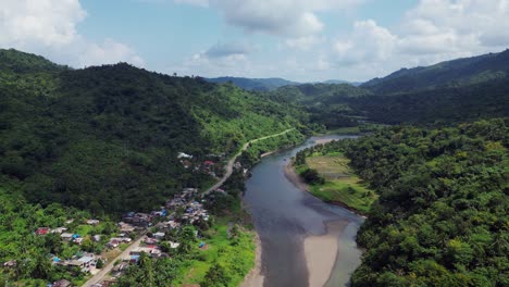 wohnhäuser entlang des flusses am fuße des grünen berges auf den philippinen