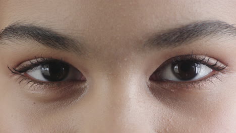 close up of woman brown eyes opening looking at camera wearing makeup cosmetics