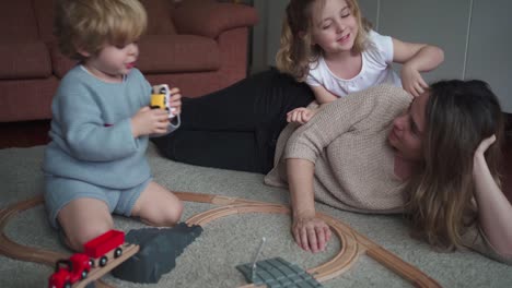 Mother-with-kids-playing-with-toy-roadway