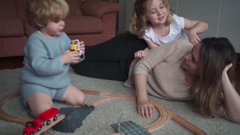 mother with kids playing with toy roadway