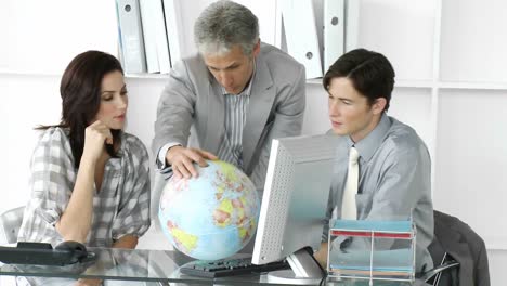 equipo de negocios afortunado mirando un globo terrestre