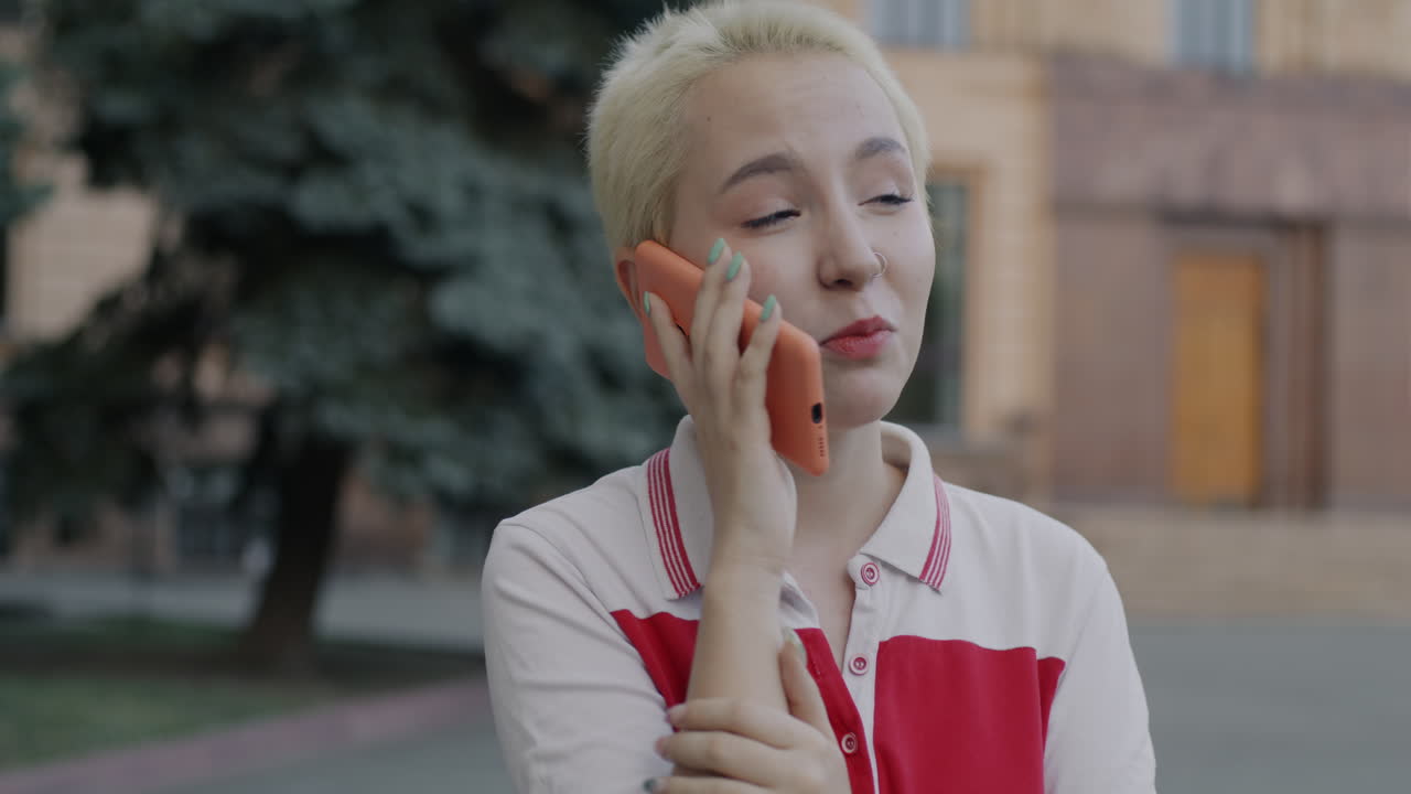 젊은 여성이 야외에서 전화로 이야기하고 있습니다.