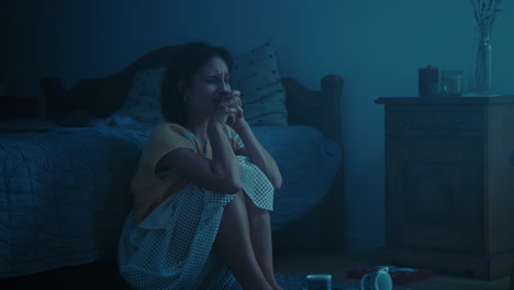 a traumatised and disoriented girl sits on the bedroom floor