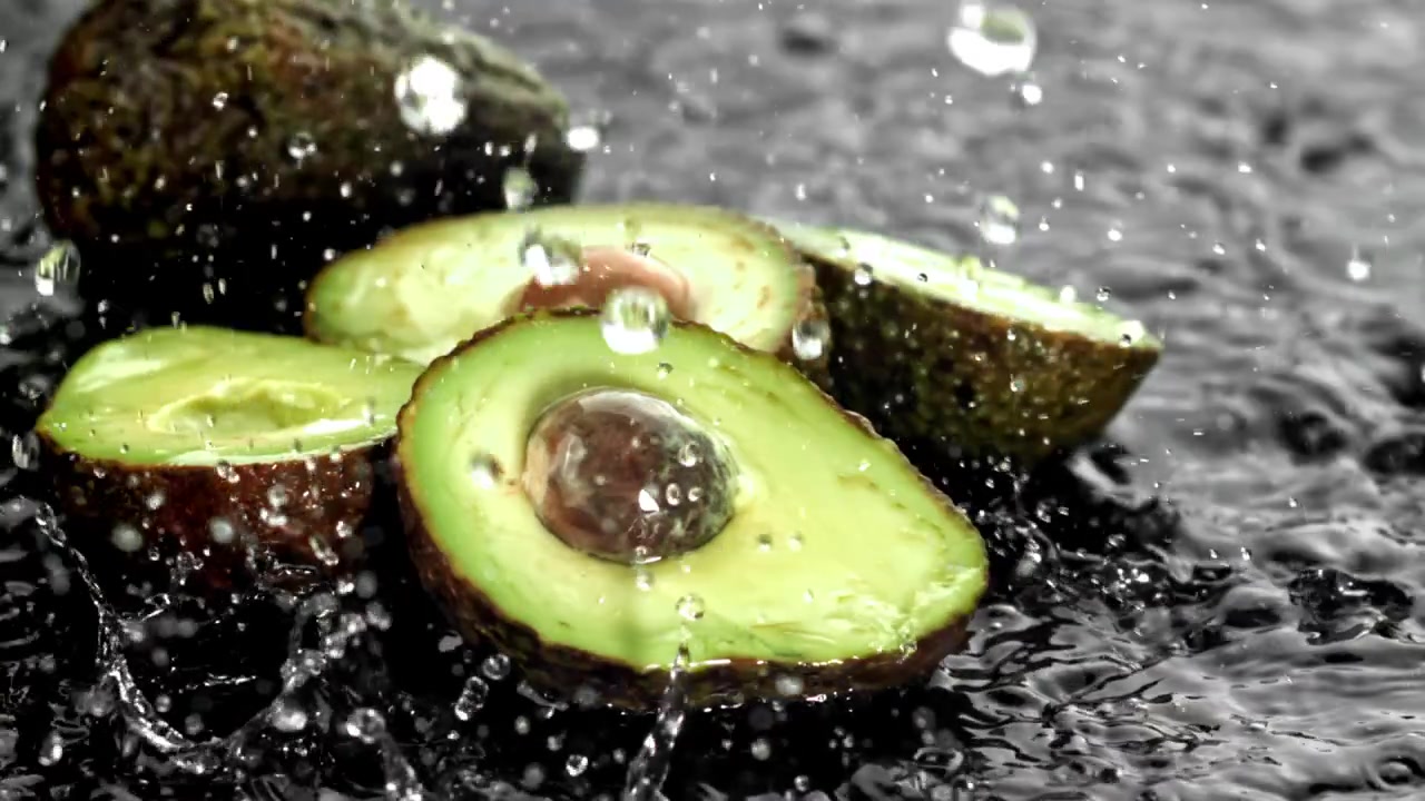 Gocce d'acqua che schizzano su avocado appena tagliati