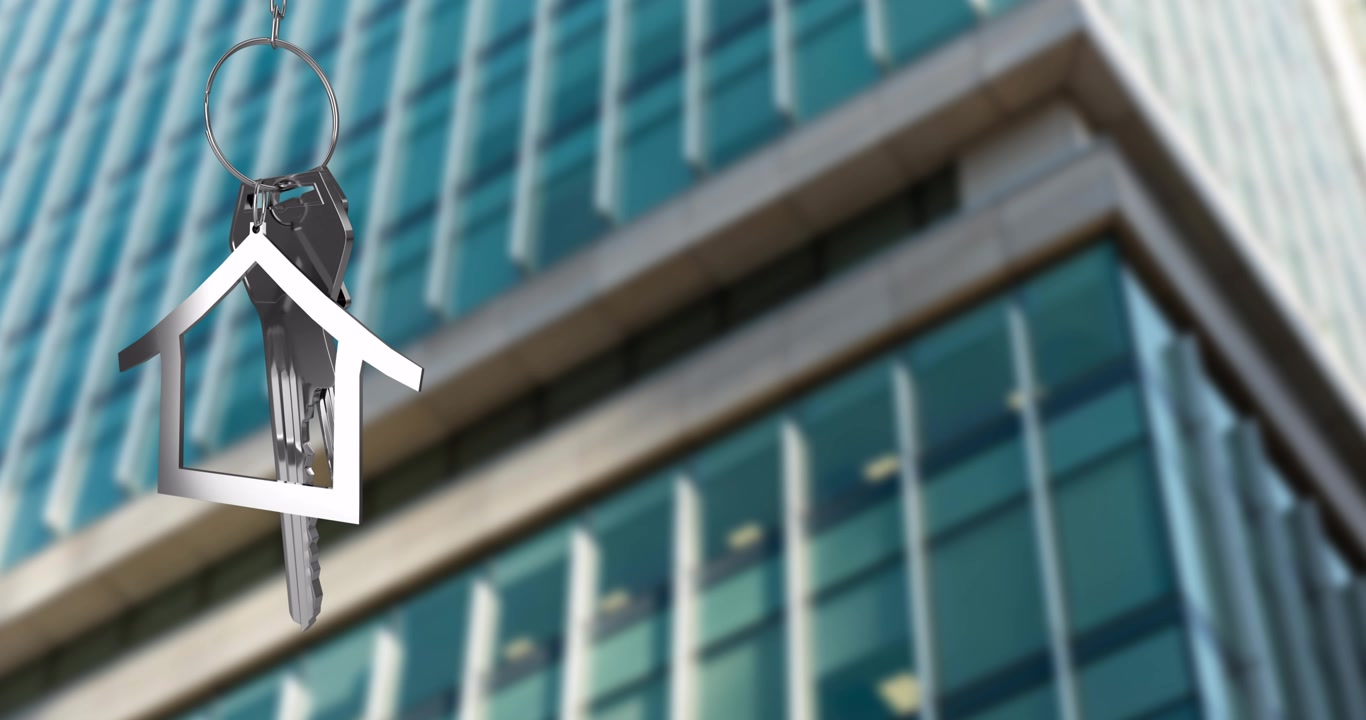 Portachiavi a forma di casa su sfondo sfocato di un moderno edificio per uffici
