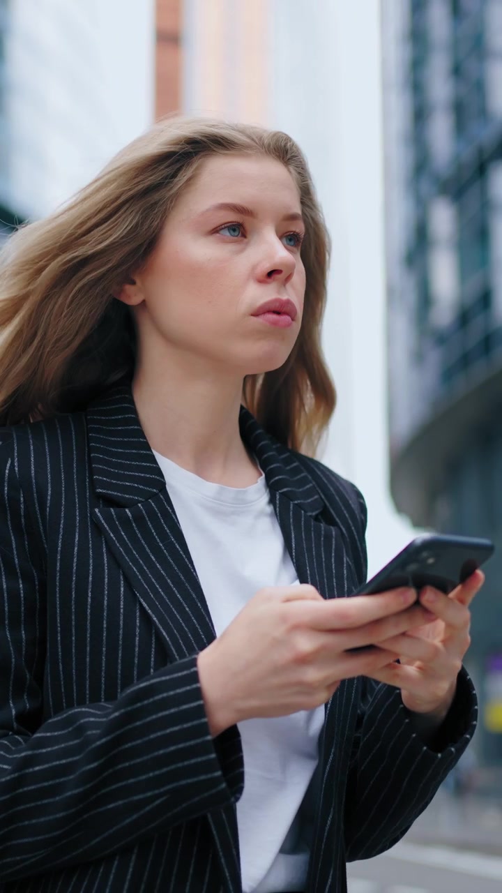 Giovane donna d'affari che usa lo smartphone all'esterno di un moderno palazzo per uffici