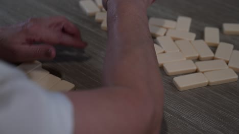 older senior citizen female domino player shuffles the dominoes and starts drawing her hand