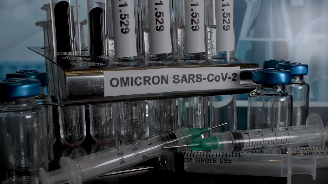 Close up dolly shot of medical equipment labelled with Omicron SARS-CoV-2 the new strain of Covid 19, tracking back as glass test tubes are placed in a laboratory rack