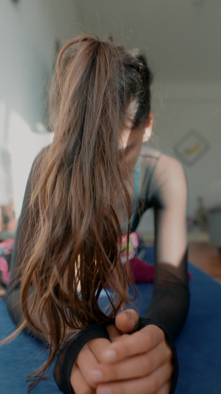 Mujer joven estirándose en una esterilla de yoga en una habitación soleada