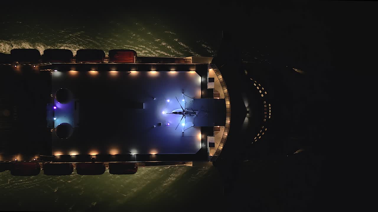 Top down drone shot of The Queen Mary 2 ocean liner sailing past at night