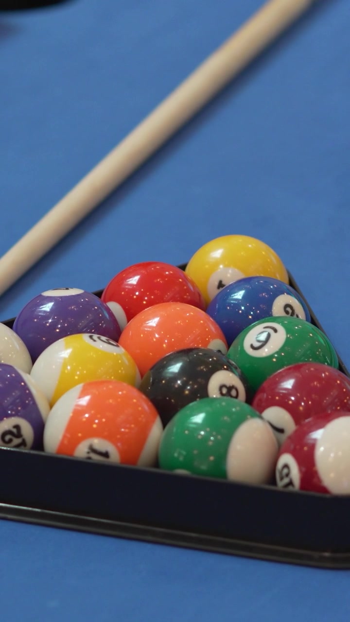 Close-up of pool table with nine-ball triangle and a white ball in a professional tournament.