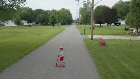 a child rides a scooter down a peaceful suburban street, surrounded by green lawns and trees. perfect for family, outdoor activity, or suburban lifestyle footage.